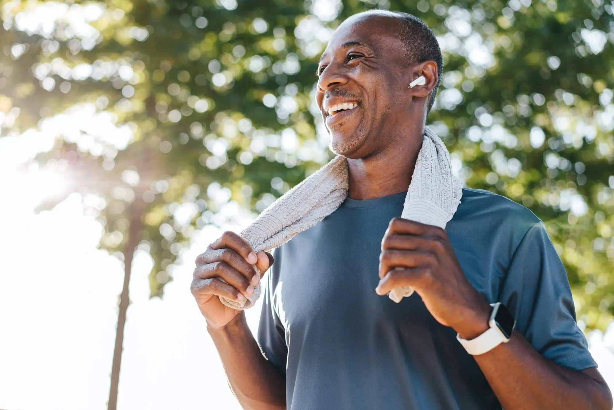 Smiling man in a blue athletic shirt, towel around neck, represent prevention and management mouth breather at Lenius Orthodontics in Overland Park, KS.