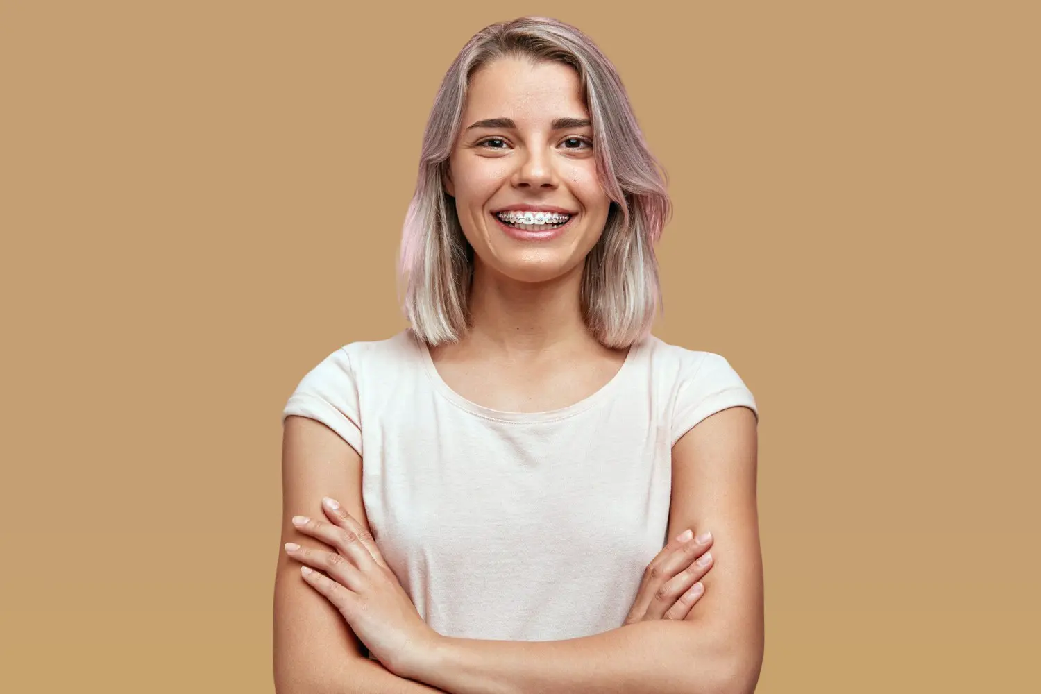Smiling young woman with braces and crossed arms exudes confidence with braces cost at Lenius Orthodontics in Overland Park, KS.