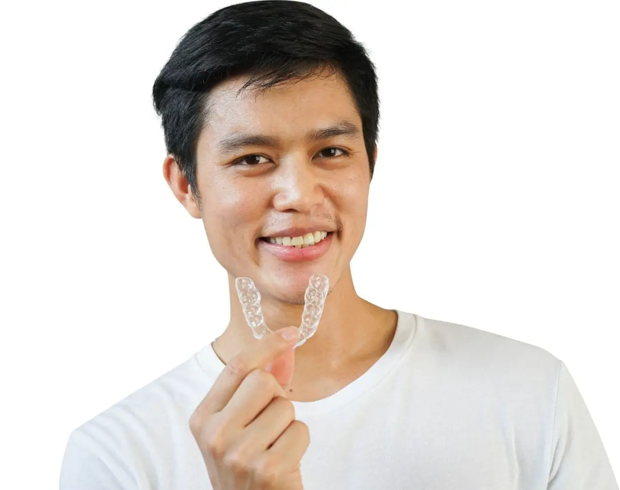 A man in a white shirt smiles, holding an Invisalign aligner, showcasing Types of Braces at Lenius Orthodontics in Overland Park, KS, on a white background.