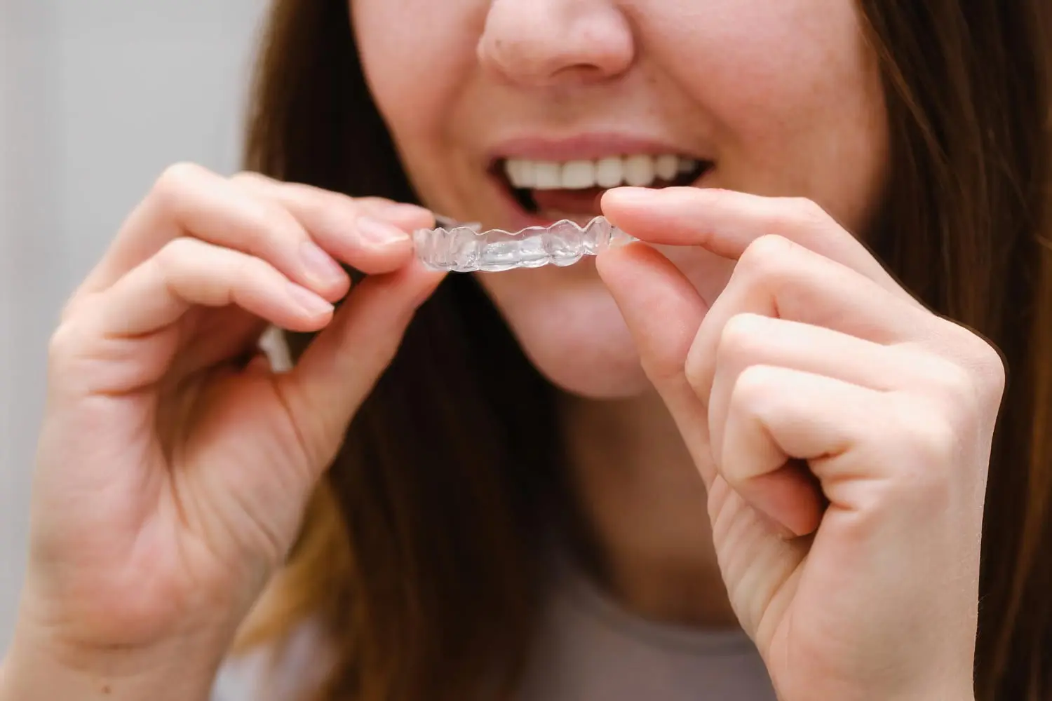 A person holds a clear dental aligner with Invisalign payment plans and Insurance from Lenius Orthodontics in Overland Park, KS.