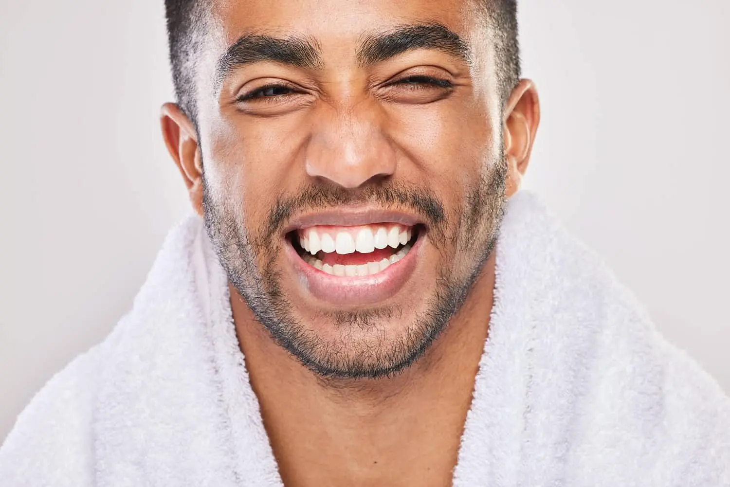A man smiles broadly, showing his teeth represent mouth breather for Lenius Orthodontics in Overland Park, KS, with a towel over his shoulders.