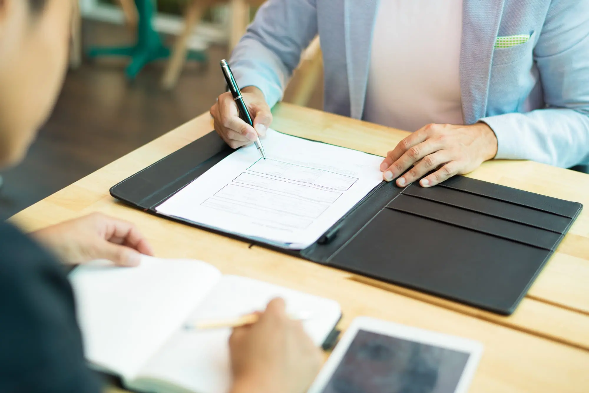 At Lenius Orthodontics in Overland Park, KS, two people complete forms at a table, possibly discussing Invisalign insurance coverage.