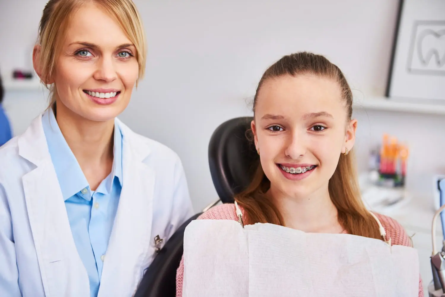 A dentist and a girl with braces smile in a dental office at Lenius Orthodontics, in Overland Park, KS, promoting Orthodontic Insurance Plans.
