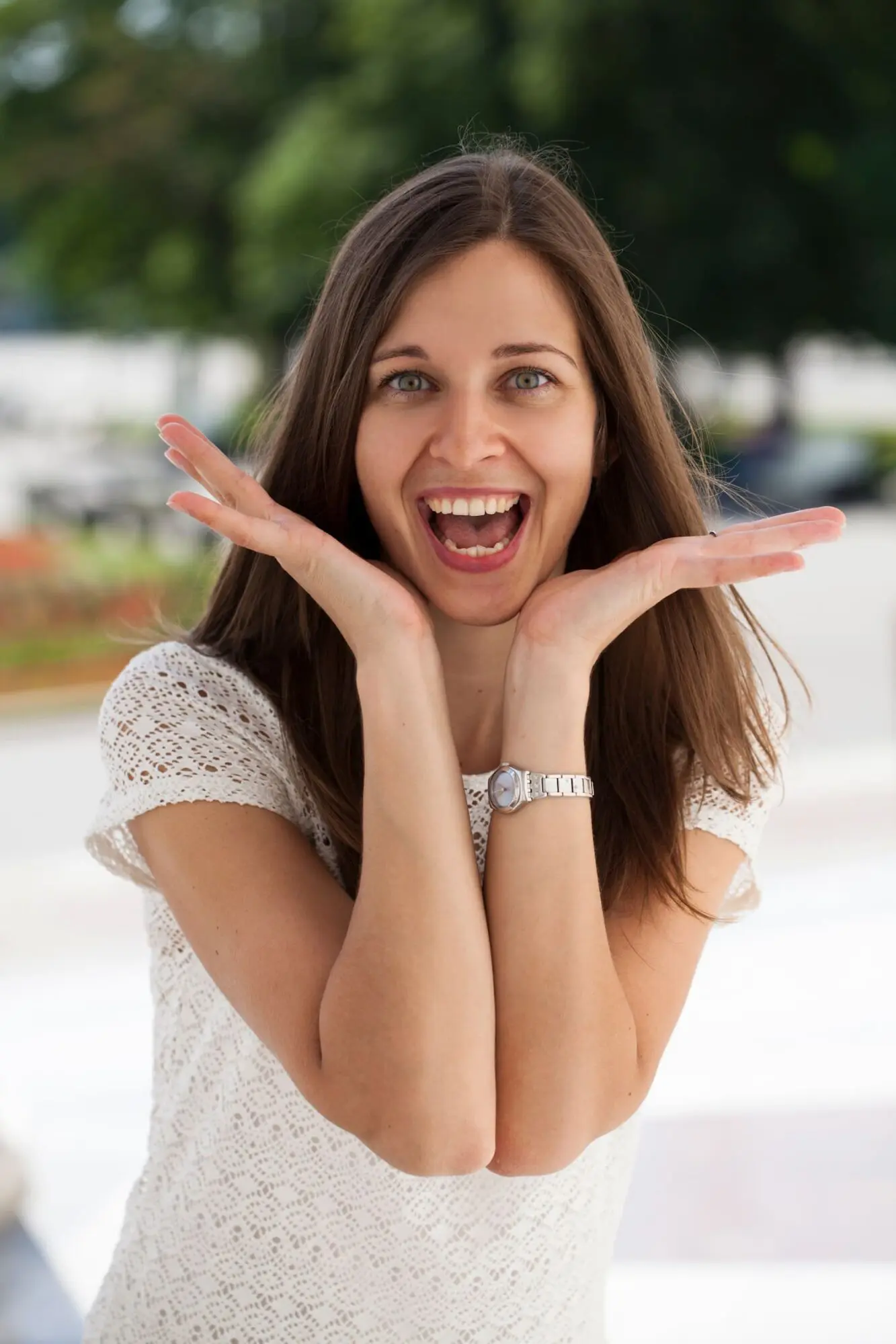 Smiling with a charming overbite, a woman poses outdoors in white lace near Lenius Orthodontics in Overland Park, KS.