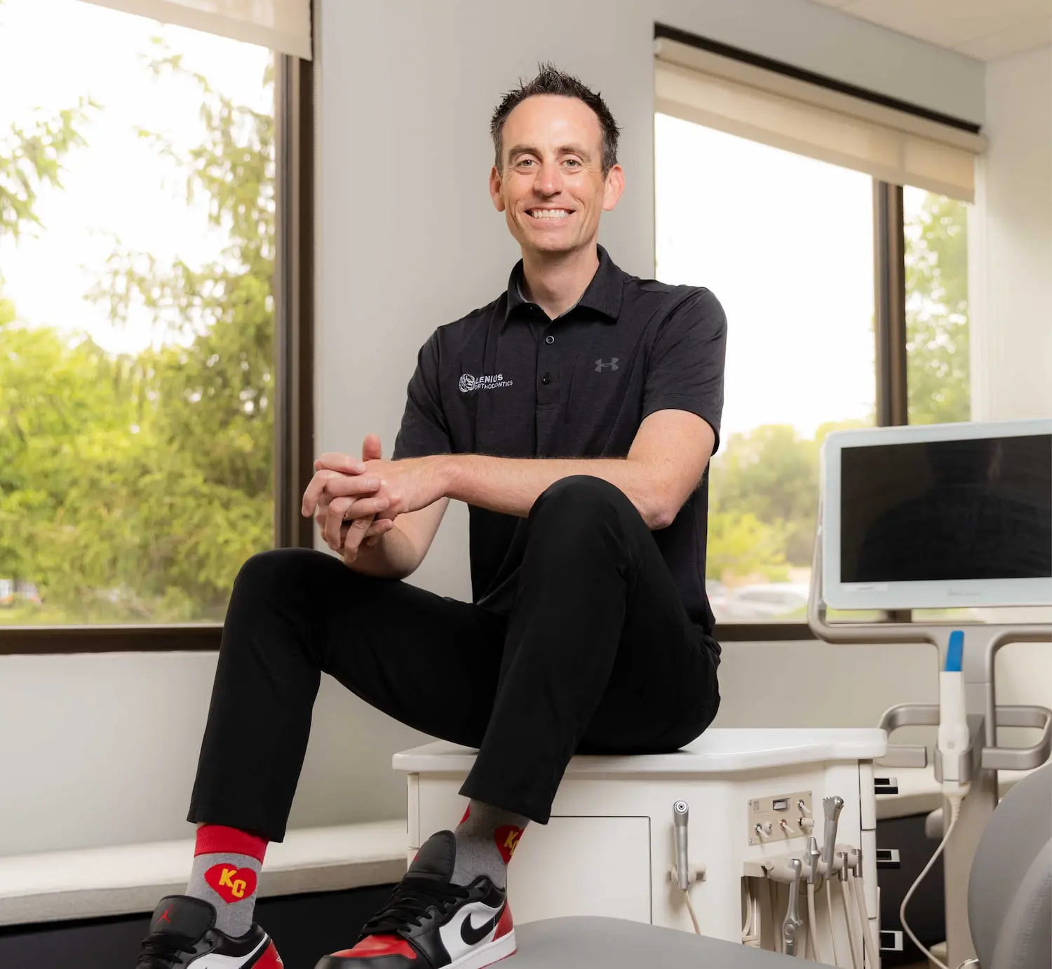 At Lenius Orthodontics in Overland Park, KS, Dr. Jeffrey Lenius, in a black polo and red socks, represents a trusted expert in dental care with braces treatment.