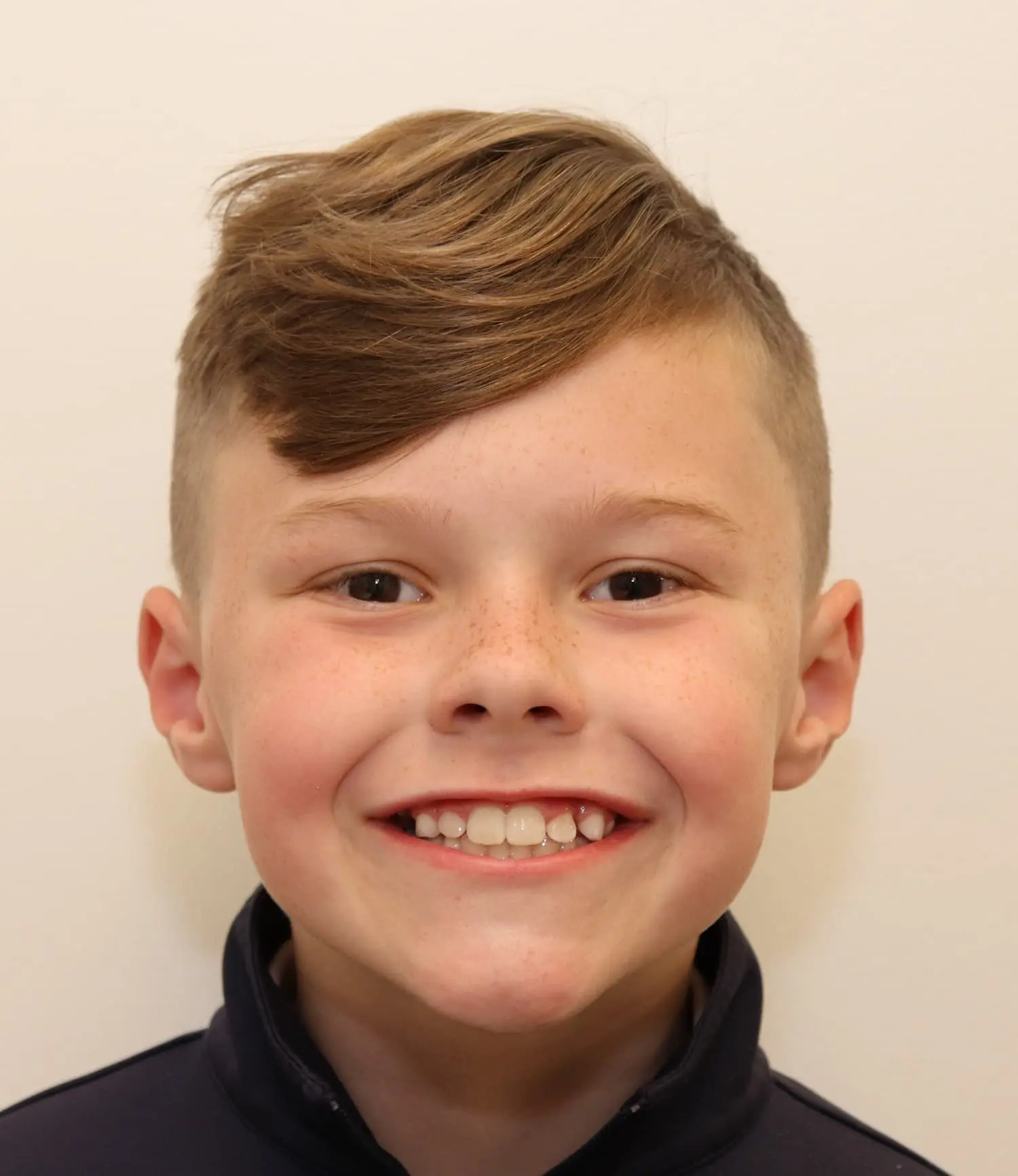 A smiling young boy with short light brown hair represents real patients and real results at Lenius Orthodontics in Overland Park, KS.