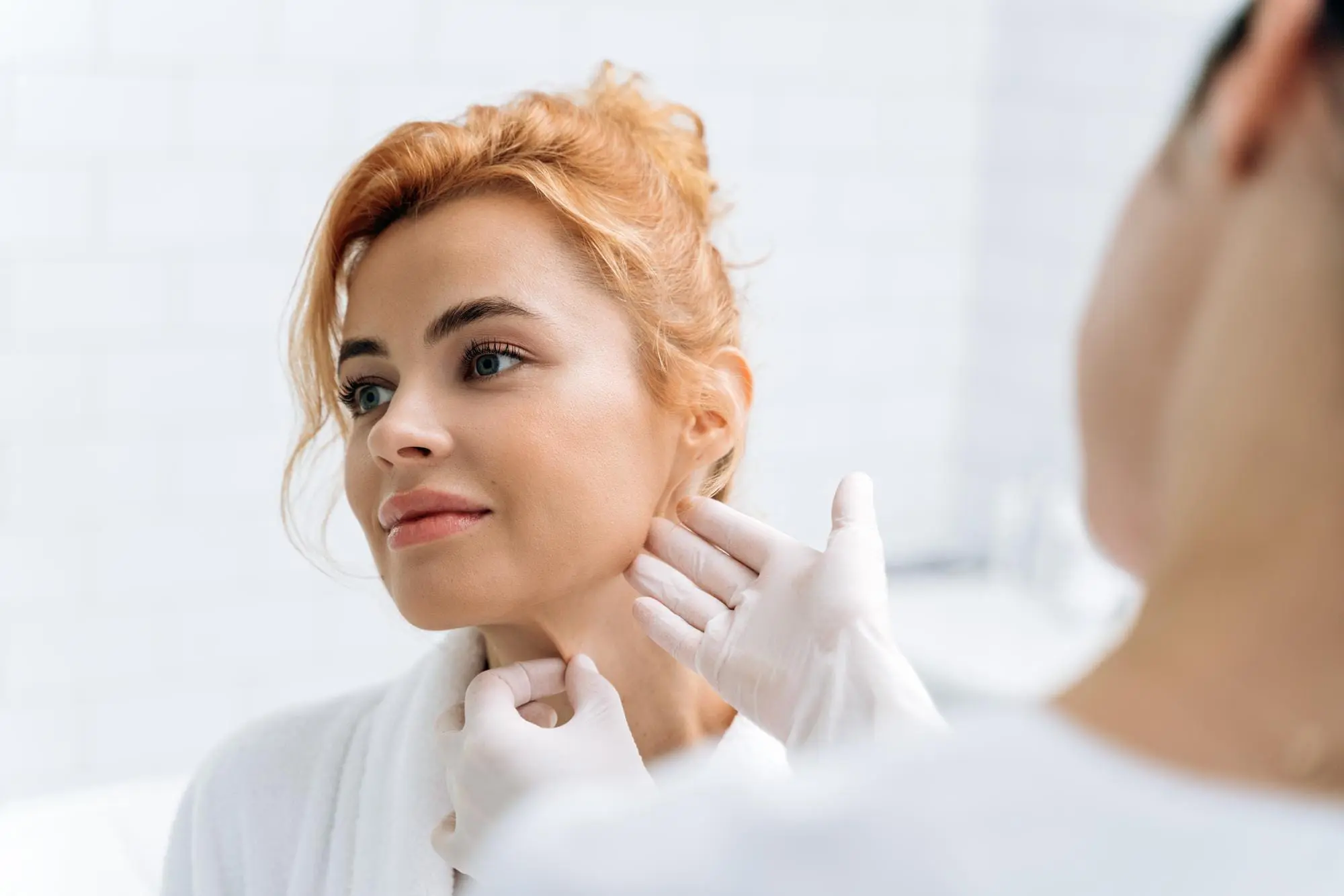 A gloved healthcare professional examines a patient’s neck at Lenius Orthodontics in Overland Park, KS, before jaw surgery.