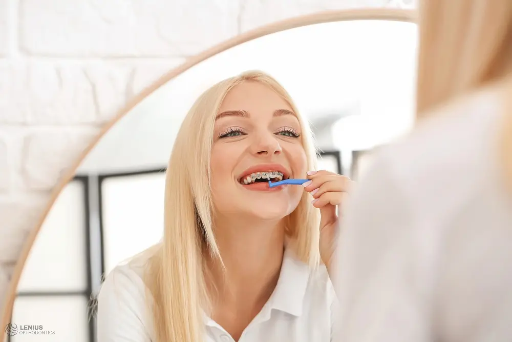 young woman metal braces toothbrush home - How to Floss with Braces in Overland Park, KS